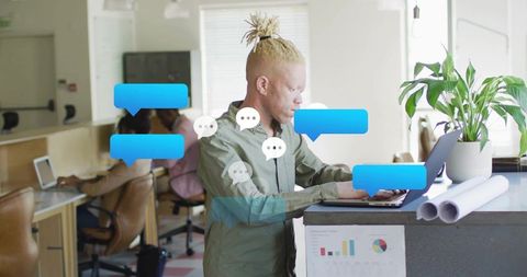 Top-knot professional typing on laptop in bright coworking hub with floating chat bubbles