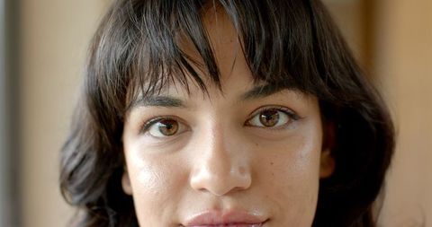 Serene woman with dark hair and freckles in soft light