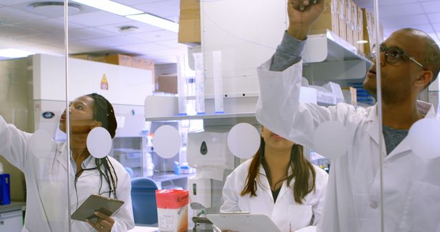 Scientists in Laboratory Writing Data on Transparent Board - Download Free Stock Images Pikwizard.com