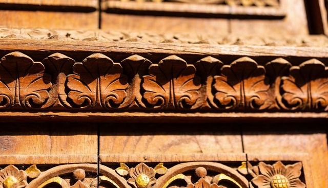 Ornate carved wooden frieze with gilded floral rosettes and palmette relief close-up