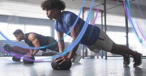 Men Performing Push-Ups on Medicine Balls in Modern Gym