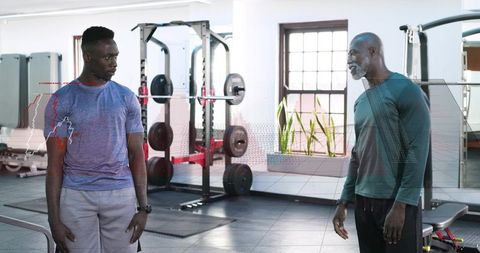 Trainer coaching client with loaded barbell for strength and form training in modern gym