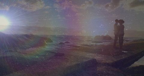 Couple Embracing on Rocky Coastline in Sunlight
