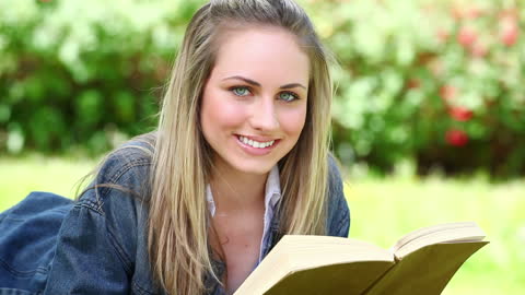 Smiling Woman Enjoying a Book in a Park Setting
