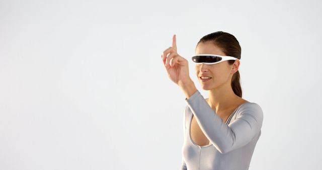 Woman wearing VR glasses interacting with a virtual interface using hand gestures. Suitable for technology-related projects, virtual reality concepts, innovation showcases, and modern device usability presentations.