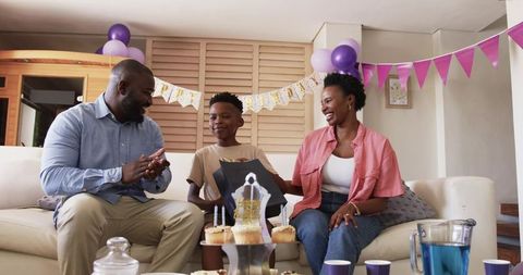African American family celebrating home birthday with cupcakes, balloons, gift bag