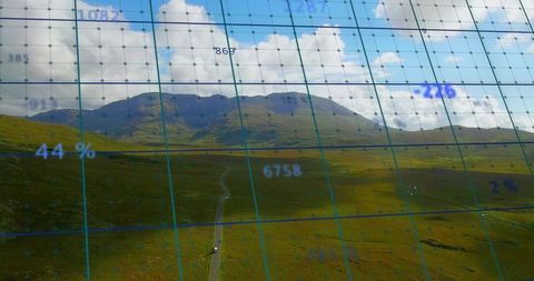 Stretching mountain ridge and winding road overlaid with blue digital grid and data