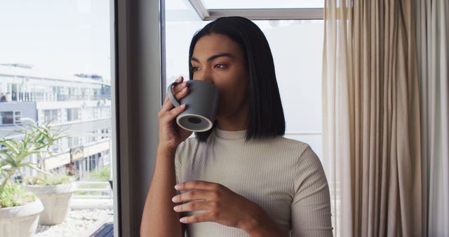 Young Woman Drinking Coffee by Window in Modern Urban Apartment - Download Free Stock Images Pikwizard.com