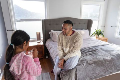 Father and daughter sharing morning moment in cozy bedroom with natural light