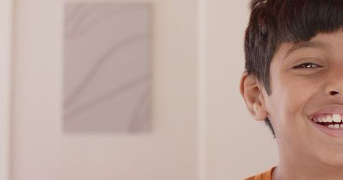 Smiling Indian Boy Against Cream Wall with Abstract Canvas
