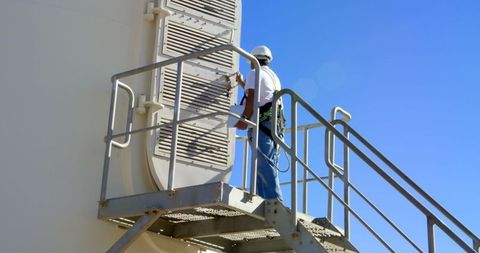 Engineer inspecting wind turbine hatch on a clear day