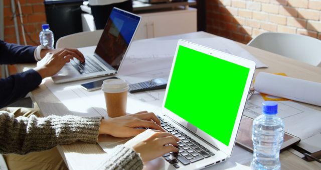 Team collaborating on laptops in modern office with green screen display - Download Free Stock Images Pikwizard.com