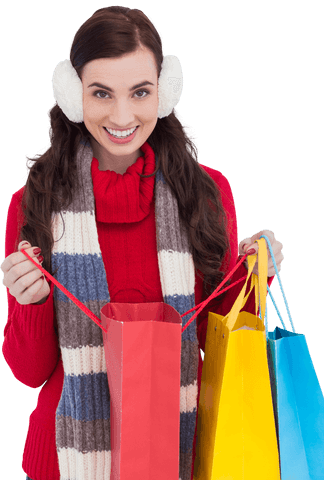 Happy woman wearing ear muffs holding colorful transparent shopping bags