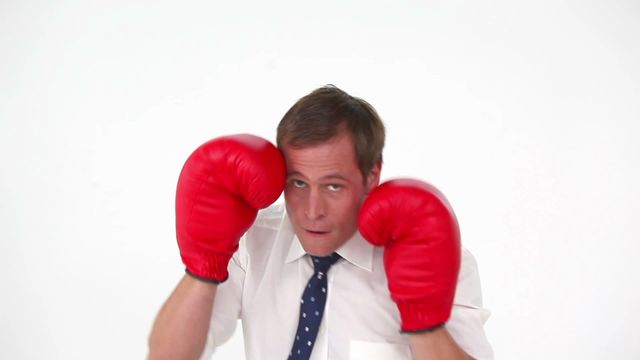 Businessman wearing boxing gloves, demonstrating determination and competitive spirit. Great for themes of business challenges, motivation, professional strength, corporate competition, perseverance, and resilience.