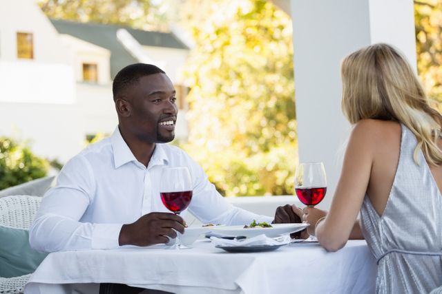 Young couple holding red wineglasses while sitting at restaurant