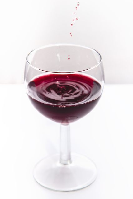 Close-up of a wine glass filled with rich red wine, showcasing delicate droplets and ripples on the surface. Ideal for use in marketing materials, wine advertisements, and dining decor. This visual represents luxury, sophistication, and celebration, perfect for promotions or articles related to beverages, wine tasting, and fine dining experiences.