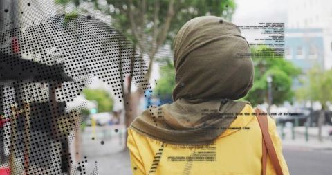 Walking woman wearing olive headscarf and yellow coat on textured urban street halftone