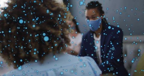 Masked consultant leading small group discussion in office with blue particle overlay