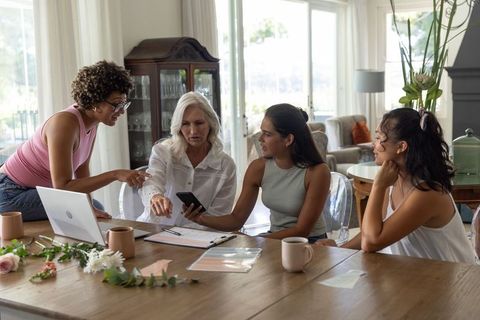 Multigenerational women planning home project, collaborating at sunlit dining table