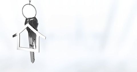 Keychain with silver house-shaped charm hanging on light background