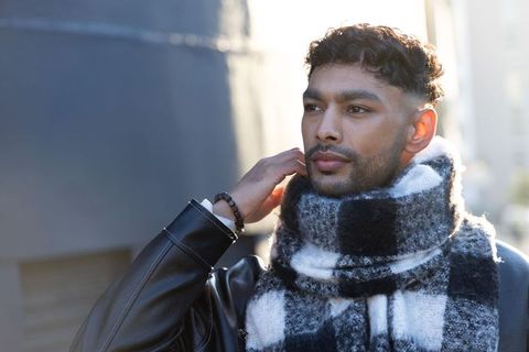 Urban winter style portrait of bearded man wearing checkered scarf and leather jacket
