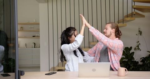 Successful Couple High-Fiving Achievements with Joy at Home
