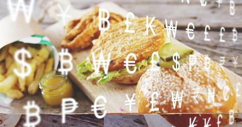 Sesame bun fried chicken sandwich with golden fries and currency symbols overlay