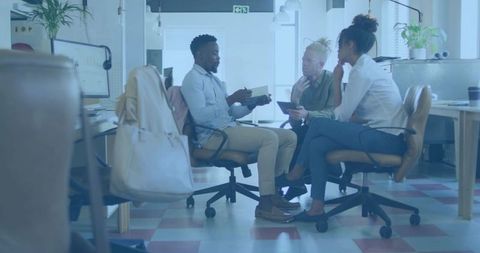 Diverse team collaborating with notebook and tablet in modern open-plan coworking office