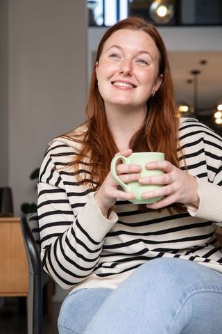 Content woman relaxing with coffee in chic modern lounge setting
