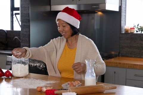 Senior Woman Wearing Santa Hat Baking in Kitchen at Home