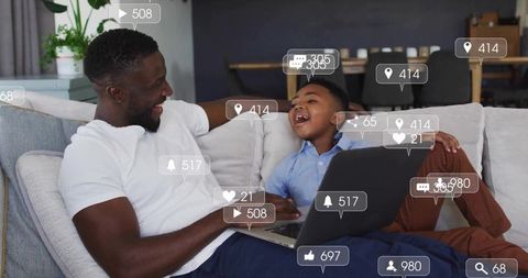 Father and Son Sharing Laptop Together on Modern Sofa
