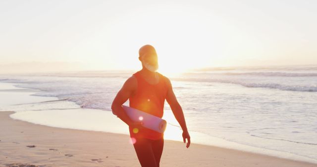 Man in Athletic Wear Walking on Beach with Yoga Mat During Sunrise - Download Free Stock Images Pikwizard.com