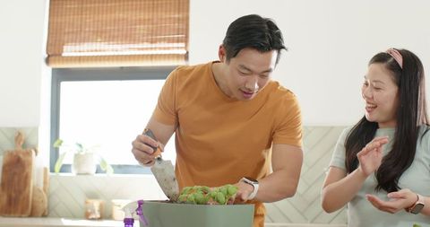 Asian couple repotting succulents on kitchen counter, cozy modern indoor gardening moment