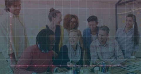 Creative team collaborating on design layouts around table with laptop and color swatches