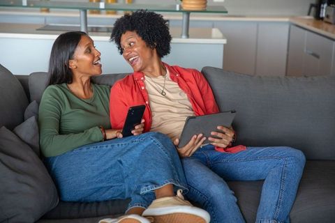 Happy couple using tablet and smartphone on sofa