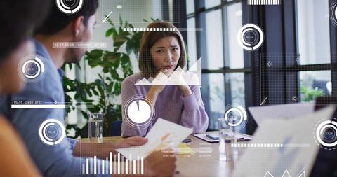 Asian woman looking pensive during team meeting with digital data overlays and charts