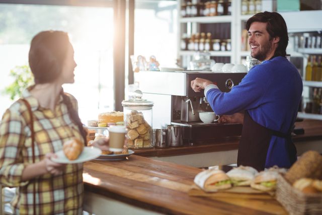 Waiter making cup of coffee while interacting with customer in cafe