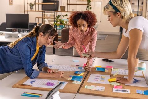 Diverse female team brainstorming on creative project in modern office