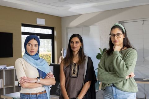 Diverse female professionals collaborating around office monitor and architectural plans
