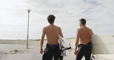Surfers Walking to Beach with Surfboards on Sunny Day