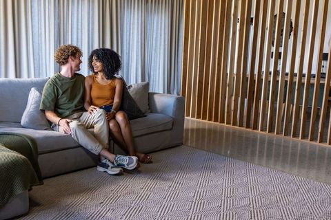 Couple relaxing on modern sofa in open-plan living room with neutral minimal decor