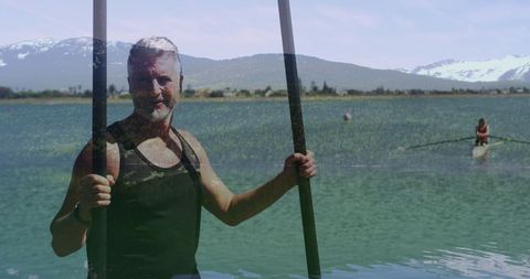 Senior Man Canoeing on Tranquil Lake with Snowy Mountain View