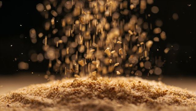 Golden-brown crumbs falling and gathering on surface