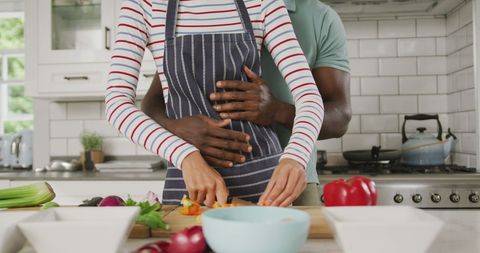 Diverse Couple Embracing While Cooking Together in Modern Kitchen