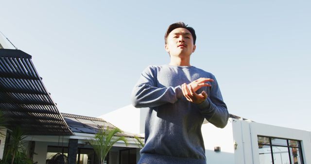 Image of relaxed biracial man exercising tai chi in garden. leisure, relax, active lifestyle and spending free time at home and garden concept.