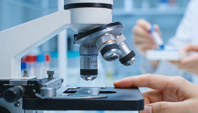 Laboratory Microscope Technician Stabilizing Slide for Clinical Research Diagnostics