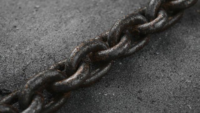 Rusty Steel Chain Diagonal Close-Up Showing Corrosion, Oil Stains and Textured Concrete