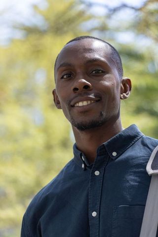 Confident african man smiling, looking at camera, wearing navy shirt and shoulder bag