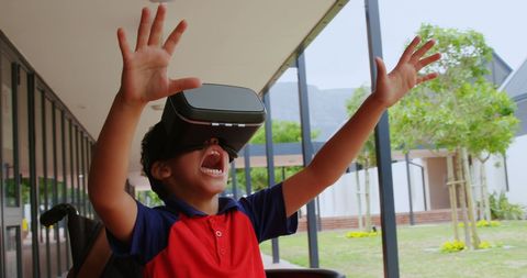 Enthusiastic schoolboy with vr headset in outdoor corridor