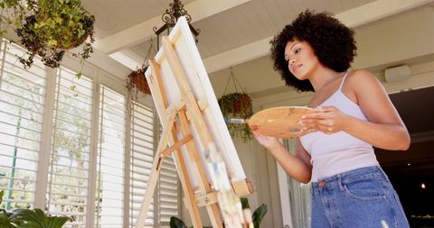 Young Woman Artist Painting on Canvas in Bright Studio